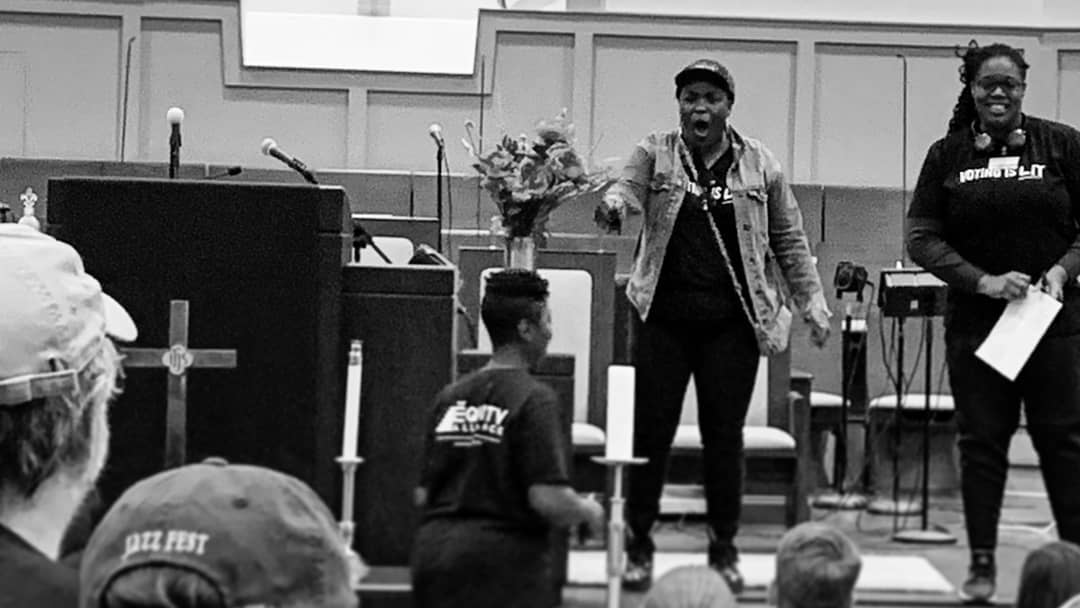 Photo of people on stage during. One is speaking emphatically, and a second person is smiling.