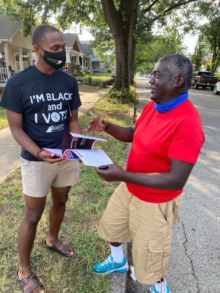 One person holding a clipboard speaking to another person.